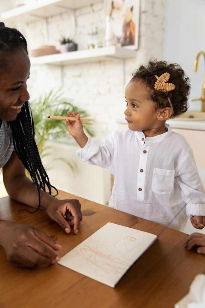 A joyful mother and daughter share a moment of creativity drawing at the table.